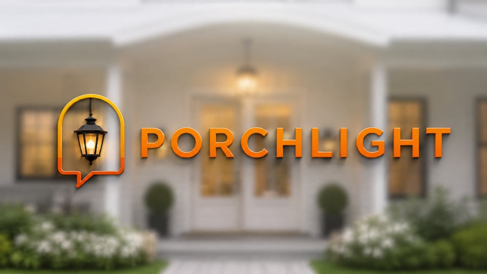 A porch light glowing above a front door at dusk